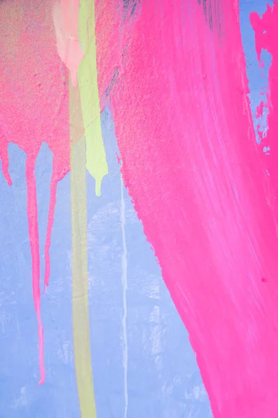 Messy paint strokes and smudges on an old painted wall. Purple, blue, pink, magenta, yellow drips, flows, streaks of paint and paint sprays.