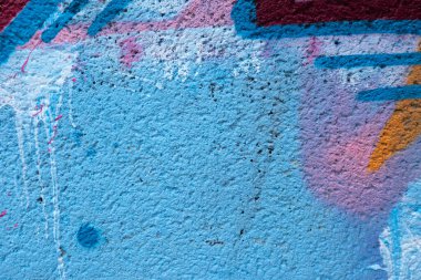 Messy paint strokes and smudges on an old painted wall background. Abstract wall surface with part of graffiti. Colorful drips, flows, streaks of paint and paint sprays.
