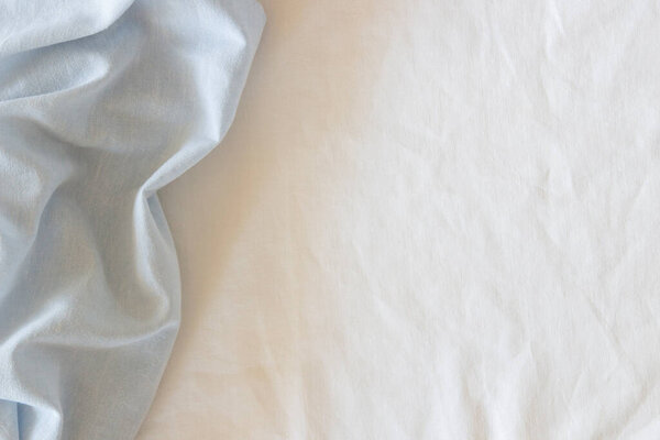 Abstract crumpled linen fabric texture background. Natural light blue hue dyed linen and white color blend linen fabric background. Top view.