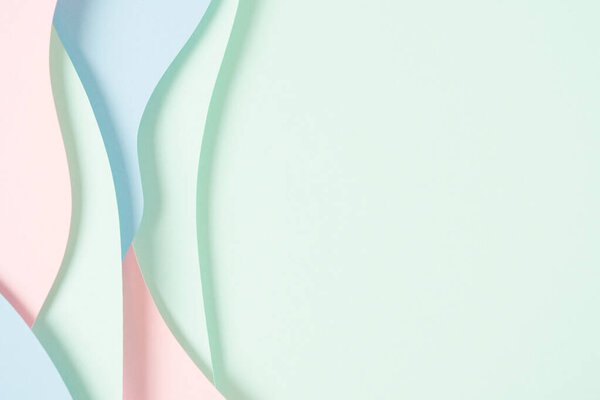 Abstract colored paper texture background. Minimal paper cut composition with layers of geometric shapes and lines in pastel green, pink and light blue colors. Top view, copy space.