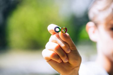 Autism infinity rainbow symbol sign in kid hand. World autism awareness day, autism rights movement, neurodiversity, autistic acceptance movement.