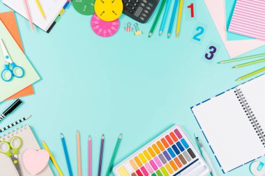Back to school background. Colored pencils, books, notebooks, pens, watercolor paint, scissors, math fractions, on pastel green background. Top view, flat lay, copy space for text.