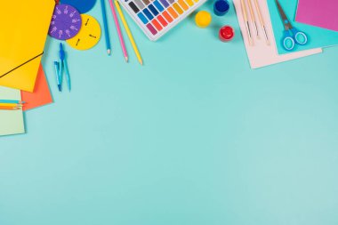 Back to school, education background. Colored pencils, books, notebooks, pens, watercolor paint, scissors, math fractions, other schooll supplies on pastel green background. Top view, flat lay
