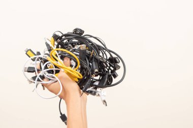 El ele tutuşan eski akıllı teknoloji kabloları, şarj kabloları ve kabloları. E-atık, planlı eskitme, elektronik bağış, elektronik atıkların imhası, geri dönüşüm konsepti.