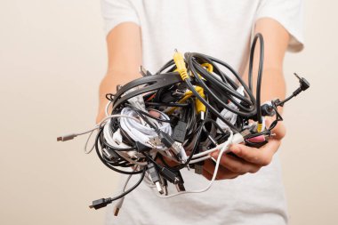 El ele tutuşan eski akıllı teknoloji kabloları, şarj kabloları ve kabloları. E-atık, planlı eskitme, elektronik bağış, elektronik atıkların imhası, geri dönüşüm konsepti.