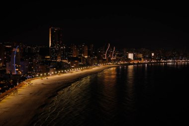 Benidorm şehrine panoramik hava manzarası, Poniente plajı, gökdelenler, şehir ışıkları ve gece Akdeniz.