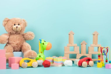 Oyuncak ayılı çocuk oyuncakları koleksiyonu, çocuk oyunları için tahta bloklar. Açık mavi arka planda renkli eğitici bebek oyuncakları. Ön görünüm.