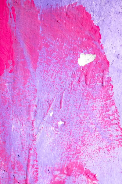 Messy paint strokes and smudges on an old painted wall. Pink, purple color drips, flows, streaks of paint and paint sprays.