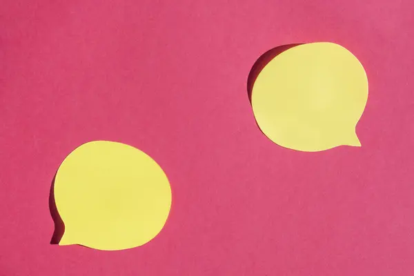 Two yellow speech bubbles on pink paper background.