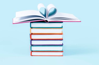 Açık mavi arkaplan üzerine kitap yığını. Eğitim, okula dönüş, kütüphane, okuma tutkusu.