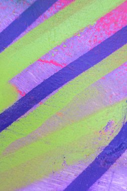 Boyanmış eski bir duvarda dağınık boya darbeleri ve lekeler. Pembe, mor, sarı damlalar, akışlar, boya ve boya püskürtüleri..