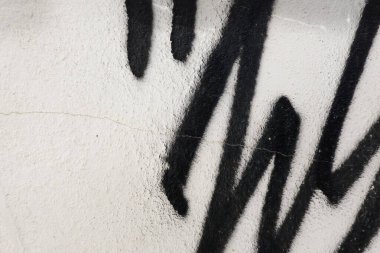 Duvar yazısının bir kısmıyla soyut duvar yüzeyi. Beyaz duvar arkaplanındaki siyah geometrik çizgiler.