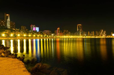 Benidorm, İspanya - 03 Temmuz 2024. Geceleri Benidorm. Benidorm şehrinin manzarası Akdeniz sularında şehir ışıklarının yansıması. Benidorm İspanya 'nın Alicante eyaletinde popüler bir tatil beldesidir..
