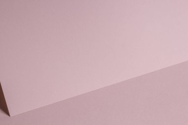 Gölgeli, boş, pastel, pembe kağıt kağıtlı bir not. Metin için kopyalama alanı olan soyut geometrik tek renkli arkaplan. Ön köşegen görünüm