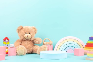 Boş podyum standı ve eğitici çocuklar için oyuncak koleksiyonu. Oyuncak ayı, tahta gökkuşağı, küp, pastel mavi arka planda ahşap eğitici bebek oyuncakları. Ön görünüm.
