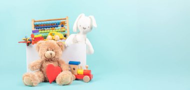 Oyuncak kutusu bebek oyuncaklarıyla dolu. Oyuncak ayılı konteynır, tüylü ve parlak mavi arka planda eğitici ahşap oyuncaklar. Küçük çocuklar için sevimli oyuncak koleksiyonu. Bağış, oyuncakçı, Salı günü vermek..