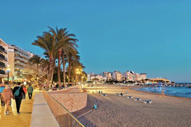 Benidorm, İspanya - 10 Ocak 2025: Poniente plajı yakınlarında deniz kenarı gezisi. İnsanlar popüler İspanyol tatil beldesinde akşamın tadını çıkarıyor.