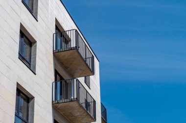 Pencereleri ve balkonları olan yeni inşa edilmiş binanın ön cephesi. İnşaat halindeki çok katlı bina, düşük açılı..