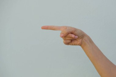 Mavi arka planda parmağı olan bir kadın. Kadın eli işaret parmağıyla boş arkaplanı işaret ediyor..