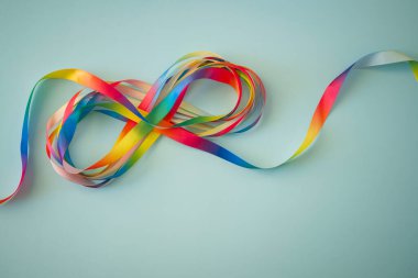 Otizm kabul ayı, Otizm Farkındalık Günü konsepti. Gökkuşağı renkli kurdeleler mavi arkaplanda sonsuz döngü şeklinde. Sonsuzluk otizm bozukluğunun sembolüdür, adhd, nöroçeşitlilik. Üst görünüm