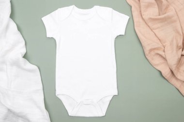 Beyaz bebek tulumu ve yeşil arka planda pamuk peçeteler. Bebek ve kızlar için uygun, boş, yeni doğmuş bebek tulumu. Model.