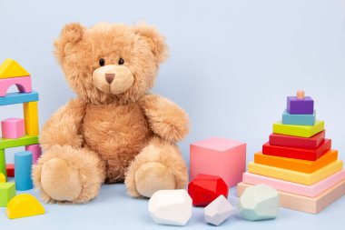 Çocuk oyuncakları geçmişi. Tatlı peluş oyuncak ayı ve açık mavi arka plandaki çocuklar için Montessori ahşap oyuncaklar. Ön görünüm.