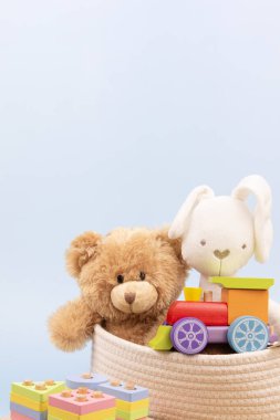 Bebek oyuncakları depoda. Oyuncak ayı, beyaz tavşan ve açık mavi arka planda eğitici ahşap oyuncaklar ve metin için kopya alanı. Ön görünüm.