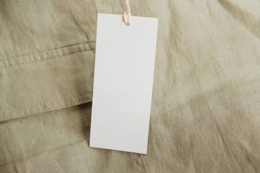 Beyaz kağıt etiketli doğal keten kumaş. Marka, metin, fiyat için kopyalama alanı olan etiket kartının boş modelleme şablonu.