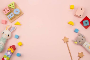 Pastel pembe arka planda oyuncak bebek çerçevesi. Doğal ahşap eğitici oyuncaklar ve çocuklar için peluş oyuncaklar. Üst görünüm, düz görünüm, metin için alanı kopyala.