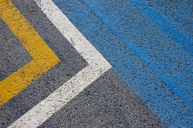 Sarı, beyaz ve maviye boyanmış asfalt çizgilere yakın çekim. Şehir sokak çevresi detayları. Üst görünüm.