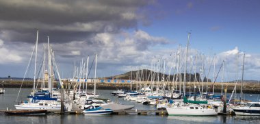 A nice day time walk along the boat dock.'Boats way in the water waves , waiting for the owner to go on trip with him. clipart