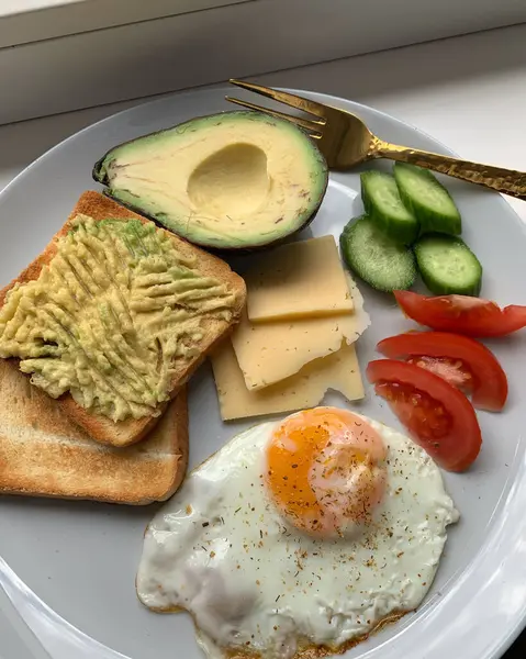 Aesthetic breakfast, scrambled eggs, avocado, cheese, sandwich and vegetables on a plate