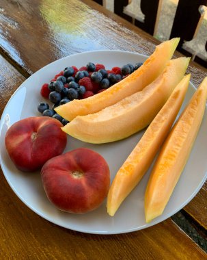 Parlak yaz meyveleri ve meyveleri ahşap bir masada bir tabakta