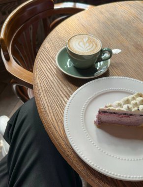 Bir fincan cappuccino ve bir parça cheesecake bir restorandaki masada