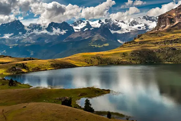 Karla kaplı tepeleri, dağlık çayırları ve etrafındaki tepeleri yansıtan kristal berrak dağ gölleriyle çarpıcı bir dağ manzarası.