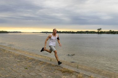 Genç adam nehir kıyısında koşuyor.