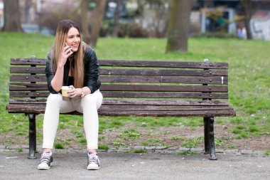 Cep telefonu ile bankta oturan neşeli kadın