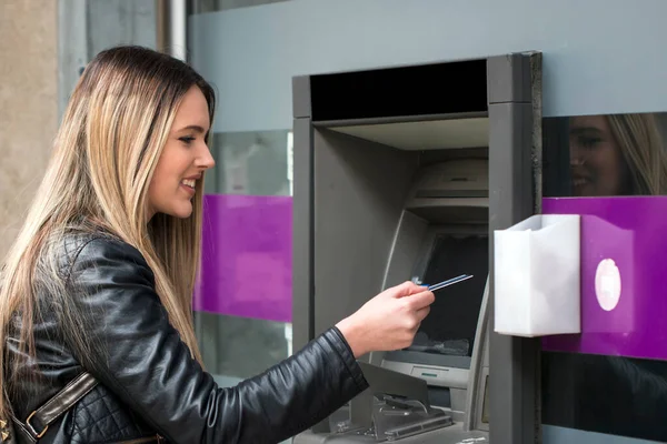 woman hand inserting credit card to ATM. Hand inserting ATM card into bank machine to withdraw money. Young Woman using Bank ATM cash machine on the street