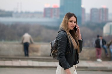 Uzak uygulama üzerinden cep telefonuna ulaşın ve Sokağı'nda gezinme sırasında arayan muhteşem dalgın kadın. Becerikli alet ile bahar kentsel ayarda yürürken boş vaktinizi rüya gibi hippi kız