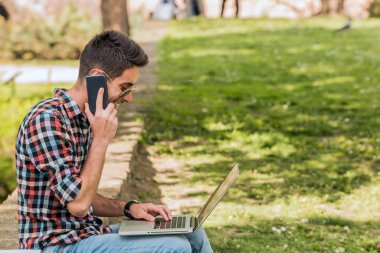 Kitabı olan bir üniversite öğrencisi. Parkta ödev yapan öğrenci..