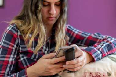 Akıllı telefon kullanan ve elinde uzaktan kumanda tutan çekici sıradan bir kadın. Etkinlik yaşam tarzları konsepti