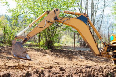 Kova kazıcısı özel bir bahçede çalışıyor. Toprağı kazıyor, arazi ve peyzaj işlerini özel makinelerle yapıyor..