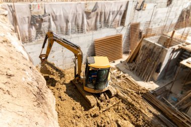 İnşaat kazıcısı inşaat alanında çalışıyor. Proje devam ediyor.