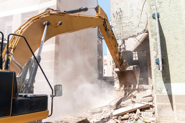 Процесс сноса старого здания демонтажа. Экскаватор ломает дом. Уничтожение ветхого жилья для новой застройки