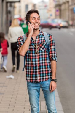 Telefonda konuşan yakışıklı bir hippi. Neşeli, olgun bir adamın cep telefonu kullanan ve gülen portresini yakından çek..