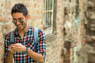 Yakışıklı adam mesaj yolluyor. Genç adam dışarıda duruyor ve mesajlaşıyor. .