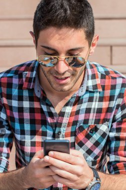 Modern adamın portresi merdivenlerde oturuyor, akıllı telefon kullanıyor. Hafta sonu için plan yapıyorum..