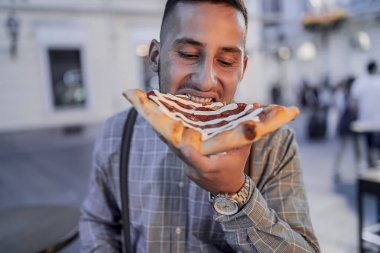Yakışıklı Gençler Gece Yarısında Şehir Caddesinde Büyük Pizzanın tadını çıkarıyor. Genç adam İtalyan yemeklerini seviyor.