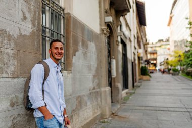 Şehir Merkezinde Duran Güneş Gözlüğü ve Sırt Çantası ile Yakışıklı İyi Giyimli Genç Adam Portresi