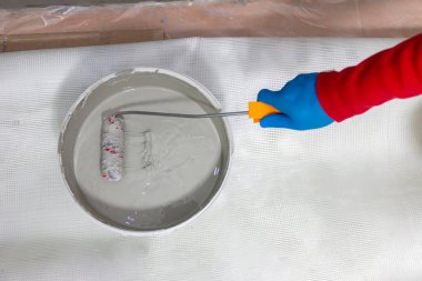 Banyo duvarına ve yere su geçirmez boya uygulayan bir inşaat işçisi. Banyoya su yalıtımı uyguluyorum..